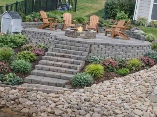 Hardscaped fire pit patio with stone steps and retaining walls built by H2Os